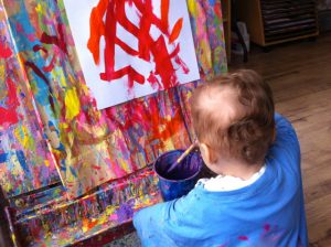 A 1-year old painting at an easel.